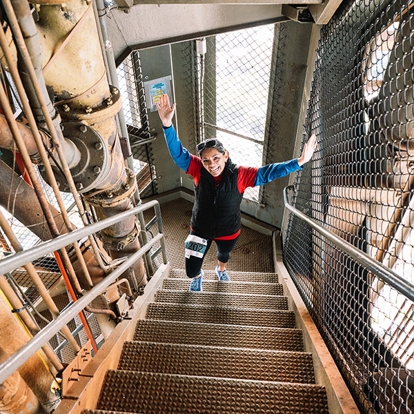 Woman in athletic clothing walking up a metal staircase.