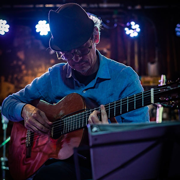 man in blue shirt and hat plays guitar