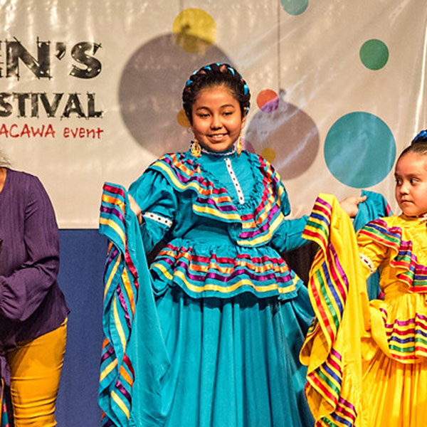 Children on stage wearing decorative dresses.