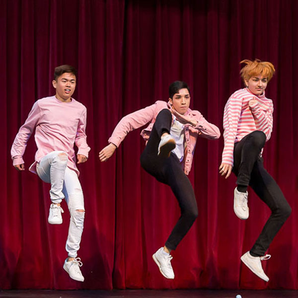 Three dancers jumping and kicking out
