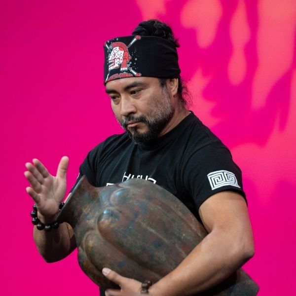 Male performer dressed in black performing with a vase.