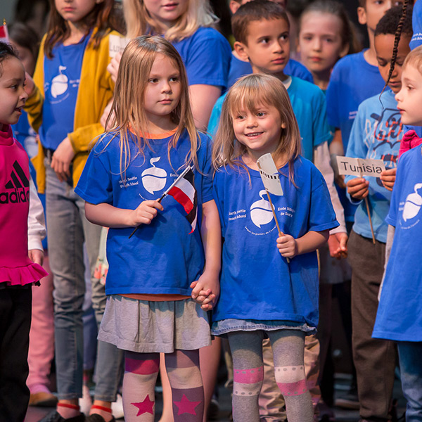 Group of diverse children in blue t-shirts holding French flags.