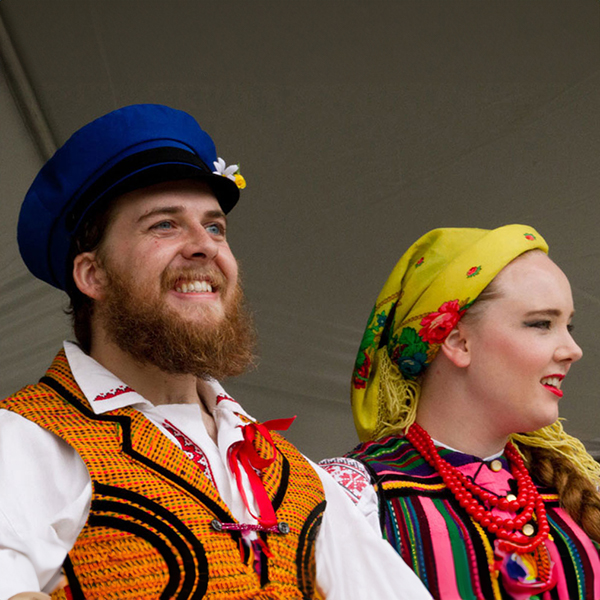Happy male and female Polish dancers in traditional outfits.