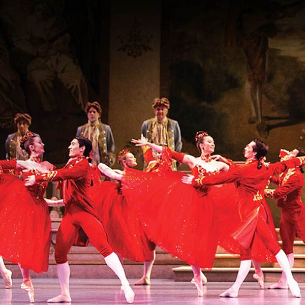 Ballet dancers performing in elegant red attire.